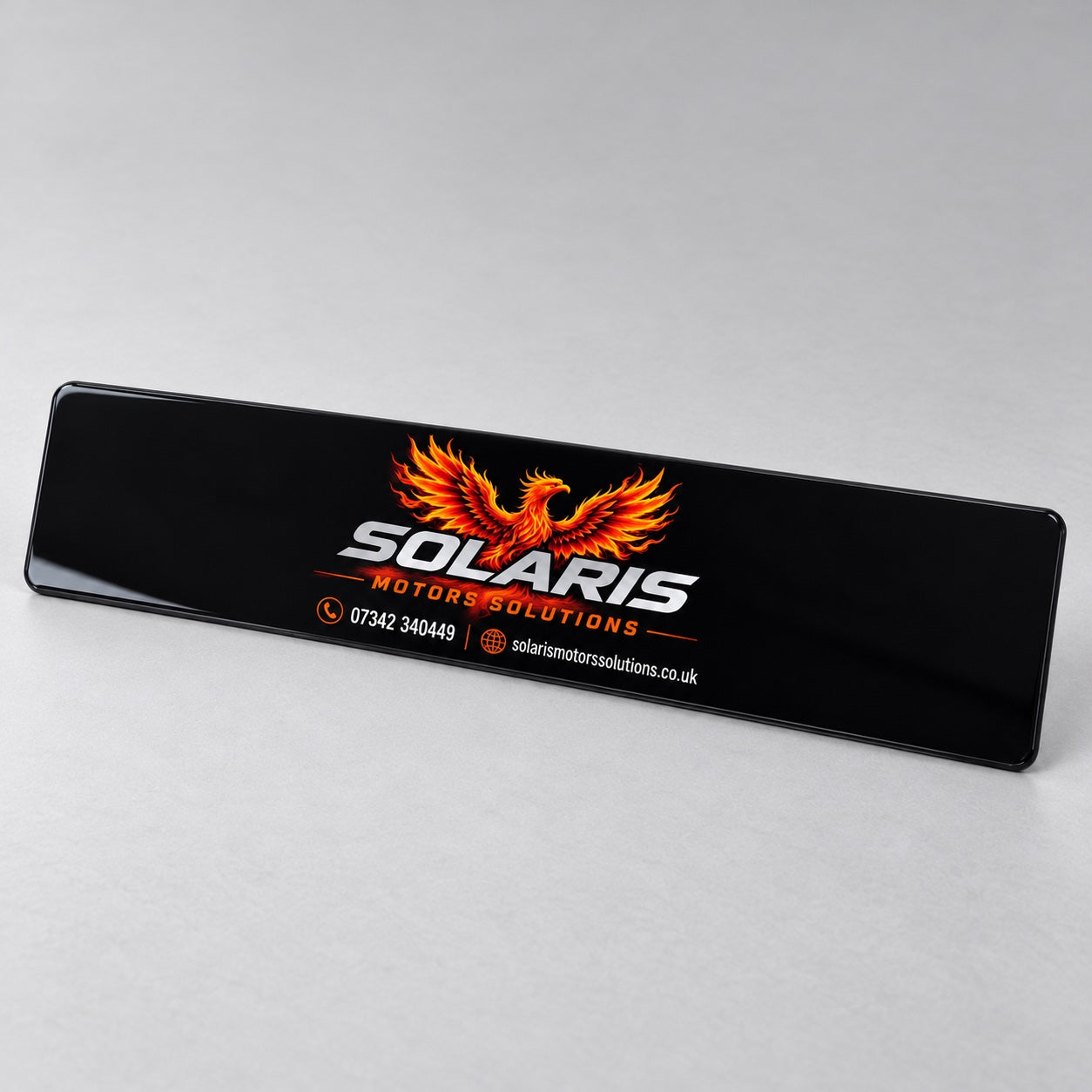 Black custom showroom number plate featuring the Solaris Motors Solutions logo and orange phoenix.