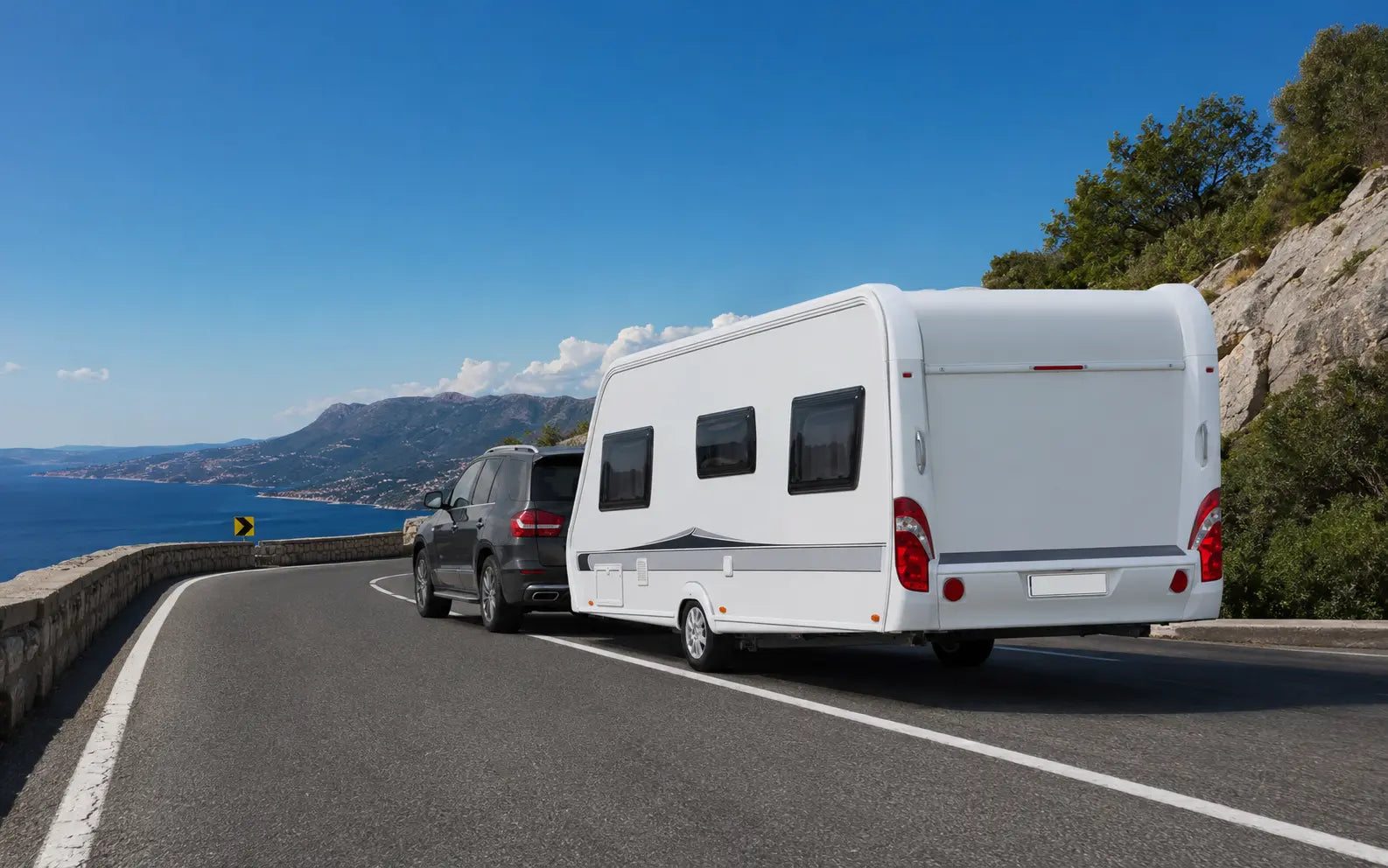 A caravan being towed on a European coastal road